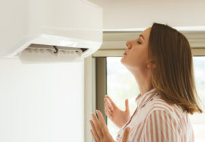 A woman enjoys a cold breeze from her ac unit